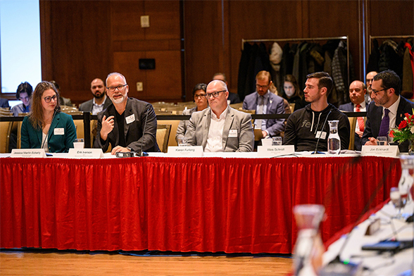 Group of people seated at a long table having a discussion.