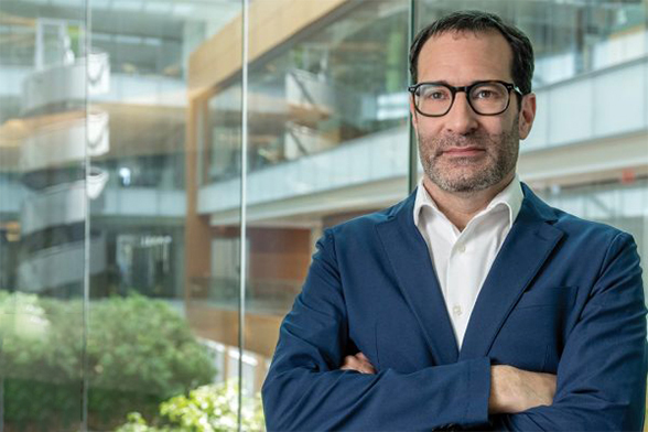 Jon Eckhardt looking off camera with arms crossed in front of a glass window.