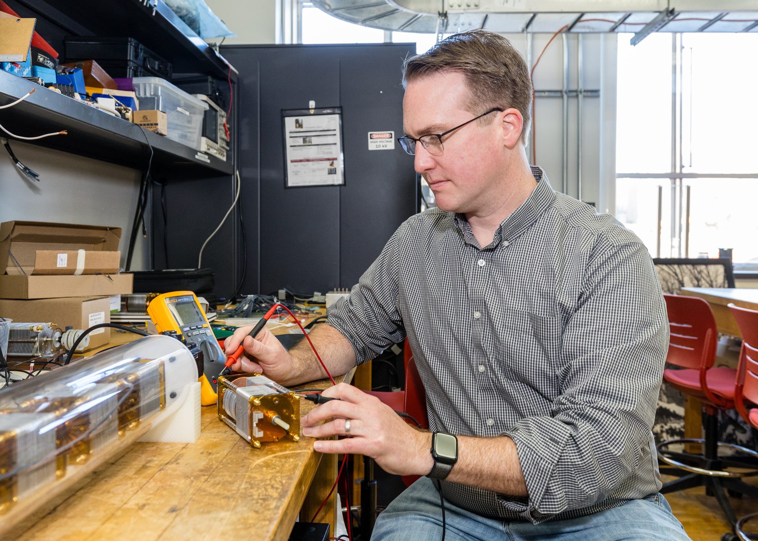 A person sits at a table in a lab working on a small electrical motor.