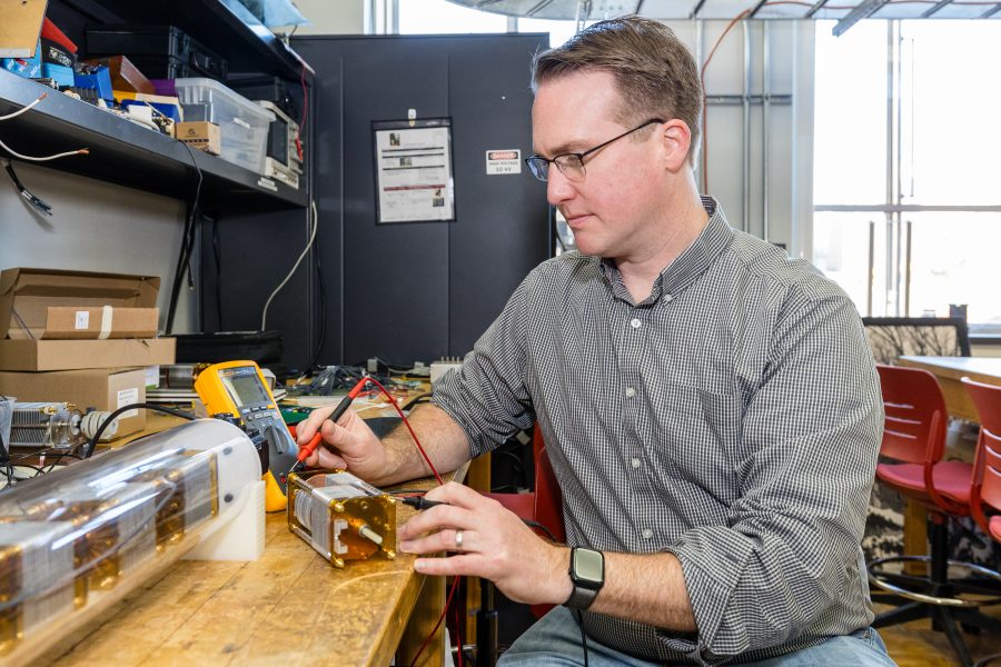 A person sits at a table in a lab working on a small electrical motor.